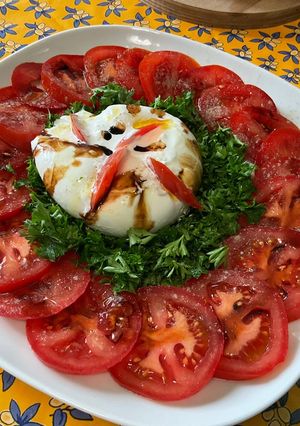 Une photo de Salade composée de tomates et persil à la mozzarella di buffala et crème de balsamique