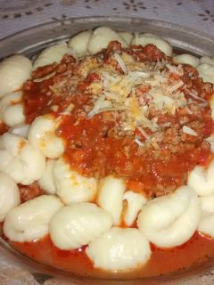 Una foto de Ñoquis de sémola y queso parmesano con salsa bologñesa 