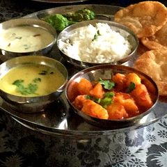 A picture of BOILED POTATO CURRY SERVED WITH KADHI, PURI, AND KHEER.