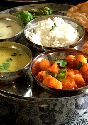 A picture of BOILED POTATO CURRY SERVED WITH KADHI, PURI, AND KHEER.