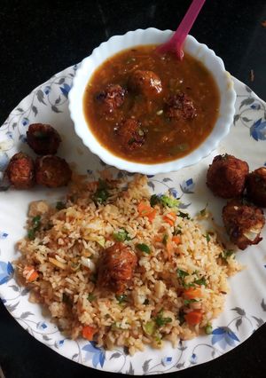 A picture of Veg fried rice with Manchurian in gravy.