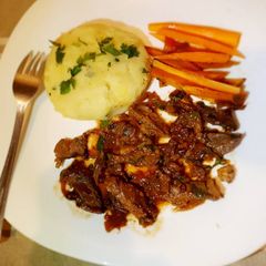 A picture of Wetfried beef, mashed potatoes and carrot sticks.