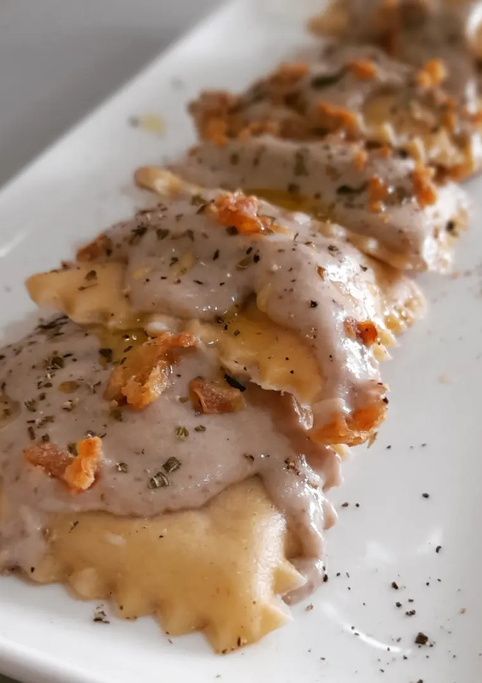 Una foto de Raviolis caseros de pies de cerdo con gambas y bechamel de ceps
