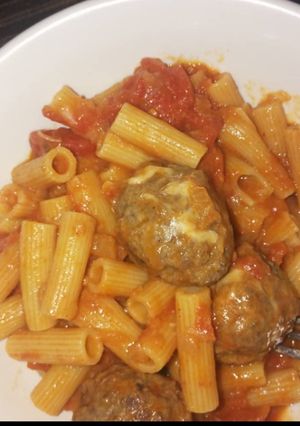 A picture of Penne pasta in tomato meatball sauce.