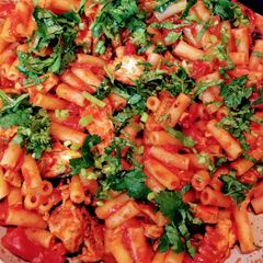 A picture of Macaroni with chicken and  tomato sauce.