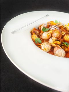 Una foto de Caracoles en salsa de tomate y jamón serrano