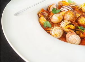 Foto principal de Caracoles en salsa de tomate y jamón serrano