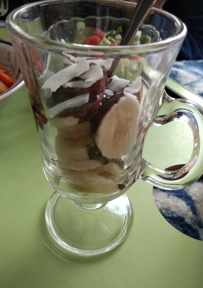 Una foto de Plátano con salsa de chocolate y láminas de coco
