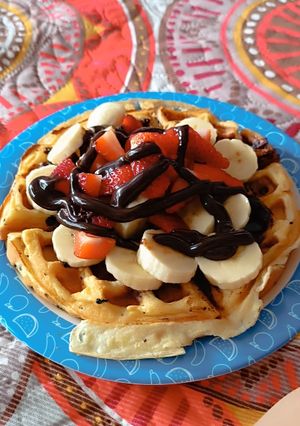 Una foto de Waflle con banano salsa de chocolate fresas y chips de chocolate