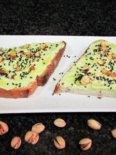 Una foto de Rebana de pan rústico con paté de aguacate y pistachos