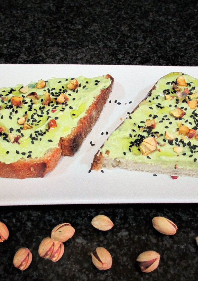 Una foto de Rebana de pan rústico con paté de aguacate y pistachos