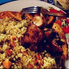 A picture of Jollof rice with fried plantain and fried chicken.