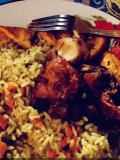 A picture of Jollof rice with fried plantain and fried chicken.