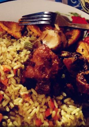 A picture of Jollof rice with fried plantain and fried chicken.
