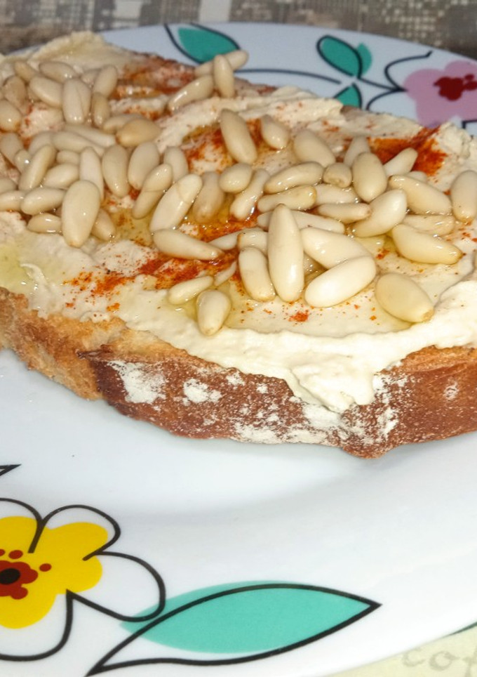 Una foto de Tostada de humus y piñones