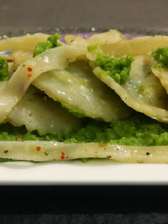 A picture of Spinich, paneer,stuffed ravioli in Green peas creamy sauce.
