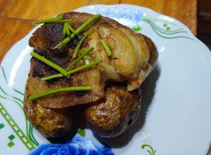 Una foto de Pollo de mar a la bolsa sobre papas rústicas enteras y cilantro