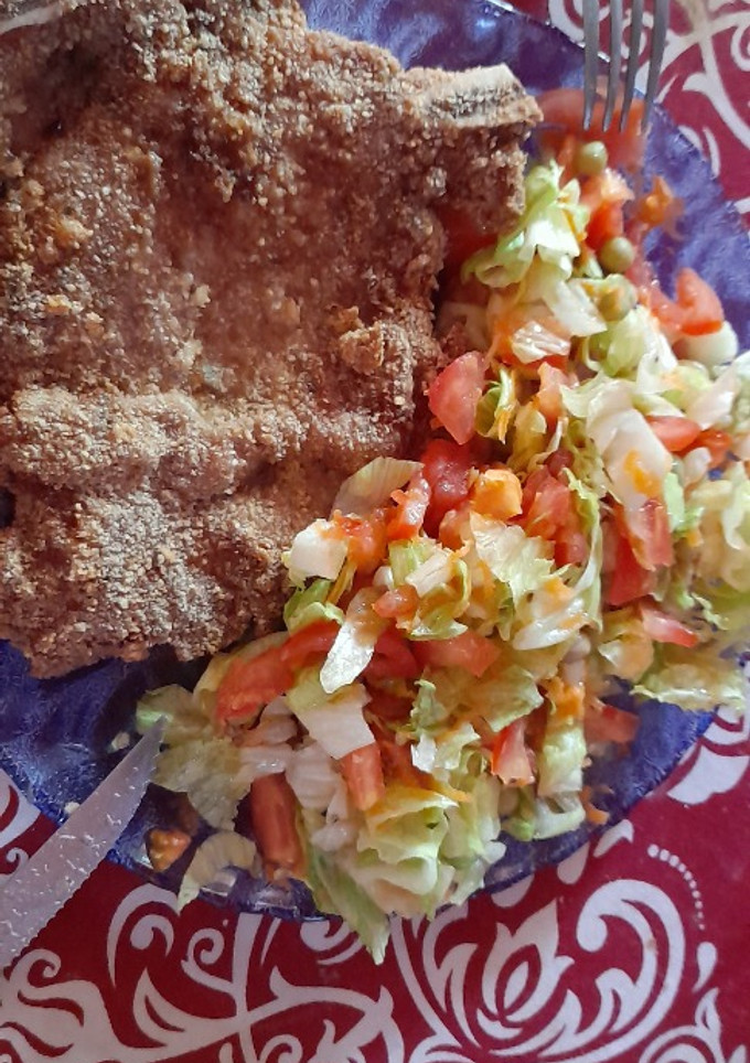 Una foto de Milanesa de chuletas, con ensalada