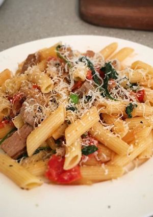 A picture of Lamb with blistered cherry tomato, spinach on penne pasta.