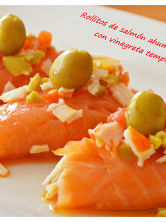 Una foto de Rollitos de salmón ahumado rellenos de gulas y vinagreta templada de tomate