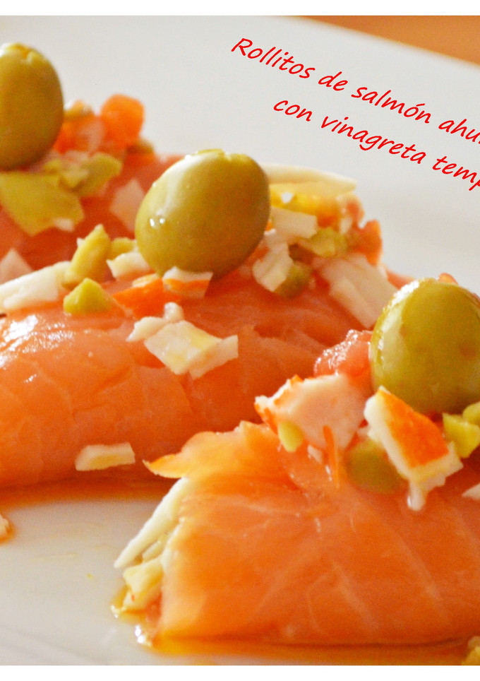Una foto de Rollitos de salmón ahumado rellenos de gulas y vinagreta templada de tomate