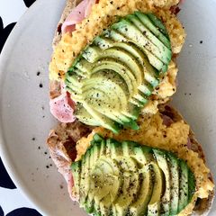 A picture of Scrambled eggs on olive bread, with bacon, mushroom and avocado 🥑.
