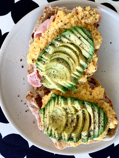 A picture of Scrambled eggs on olive bread, with bacon, mushroom and avocado 🥑.