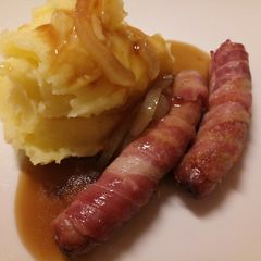 A picture of Pigs in blankets, mash and onion gravy.
