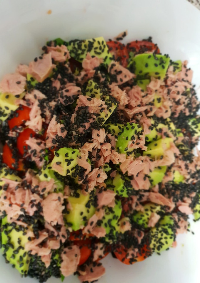 Una foto de Ensalada de tomates cherry y aguacates con semillas de sésamo negro y albahaca