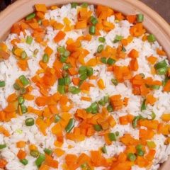 A picture of Rice with carrots and green peas.