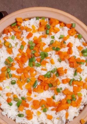 A picture of Rice with carrots and green peas.