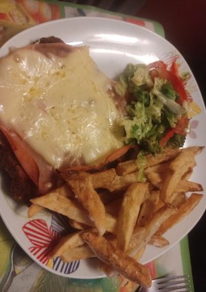 Una foto de Milanesa napolitana con fritas y ensalada