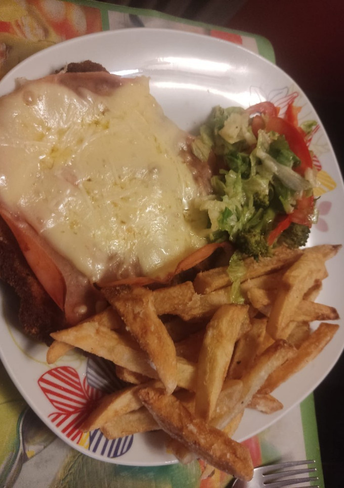 Una foto de Milanesa napolitana con fritas y ensalada