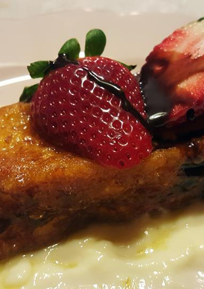 Una foto de Torrijas bañadas en almíbar de naranja sobre crema inglesa
