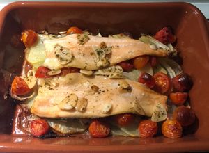 Una foto de Filetes de trucha al horno sobre cama de patatas, cebolla y tomate