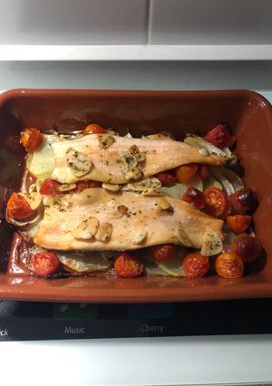 Una foto de Filetes de trucha al horno sobre cama de patatas, cebolla y tomate