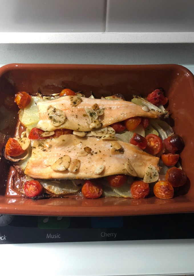 Una foto de Filetes de trucha al horno sobre cama de patatas, cebolla y tomate