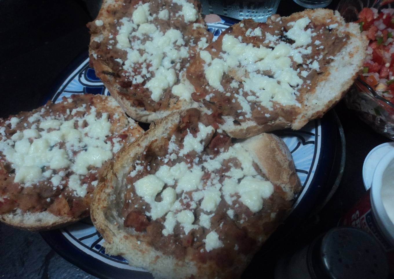 Tostaditos de bolillo con frijoles con carne y queso gratinados