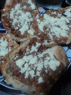 Una foto de Tostaditos de bolillo con frijoles con carne y queso gratinados