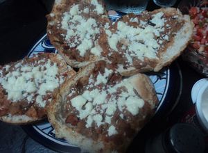 Una foto de Tostaditos de bolillo con frijoles con carne y queso gratinados