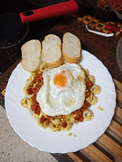 Una foto de Tortellinis con boloñesa de salchicha y chorizo y huevo frito