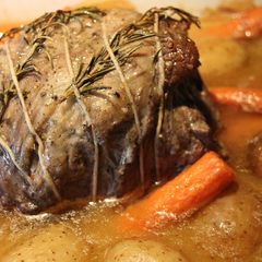 A picture of Hearb roasted leg of lamb roll with potatoes and carrots.