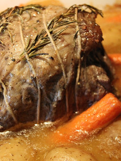 A picture of Hearb roasted leg of lamb roll with potatoes and carrots.