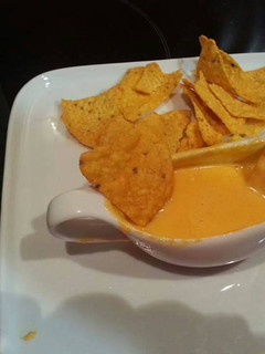Una foto de Nachos con salsa cheddar