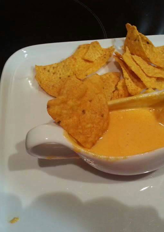Una foto de Nachos con salsa cheddar