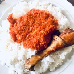 A picture of White Rice with tomato stew and chicken.