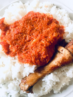 A picture of White Rice with tomato stew and chicken.