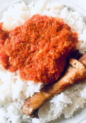 A picture of White Rice with tomato stew and chicken.