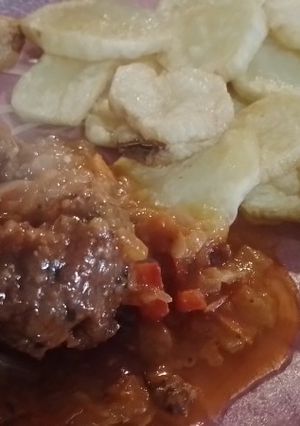Una foto de Albóndigas con queso cremoso adentro y papas fritas
