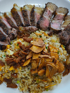 A picture of Beef Fat Fried Rice Topped with Crispy Beef Bits and Garlic.